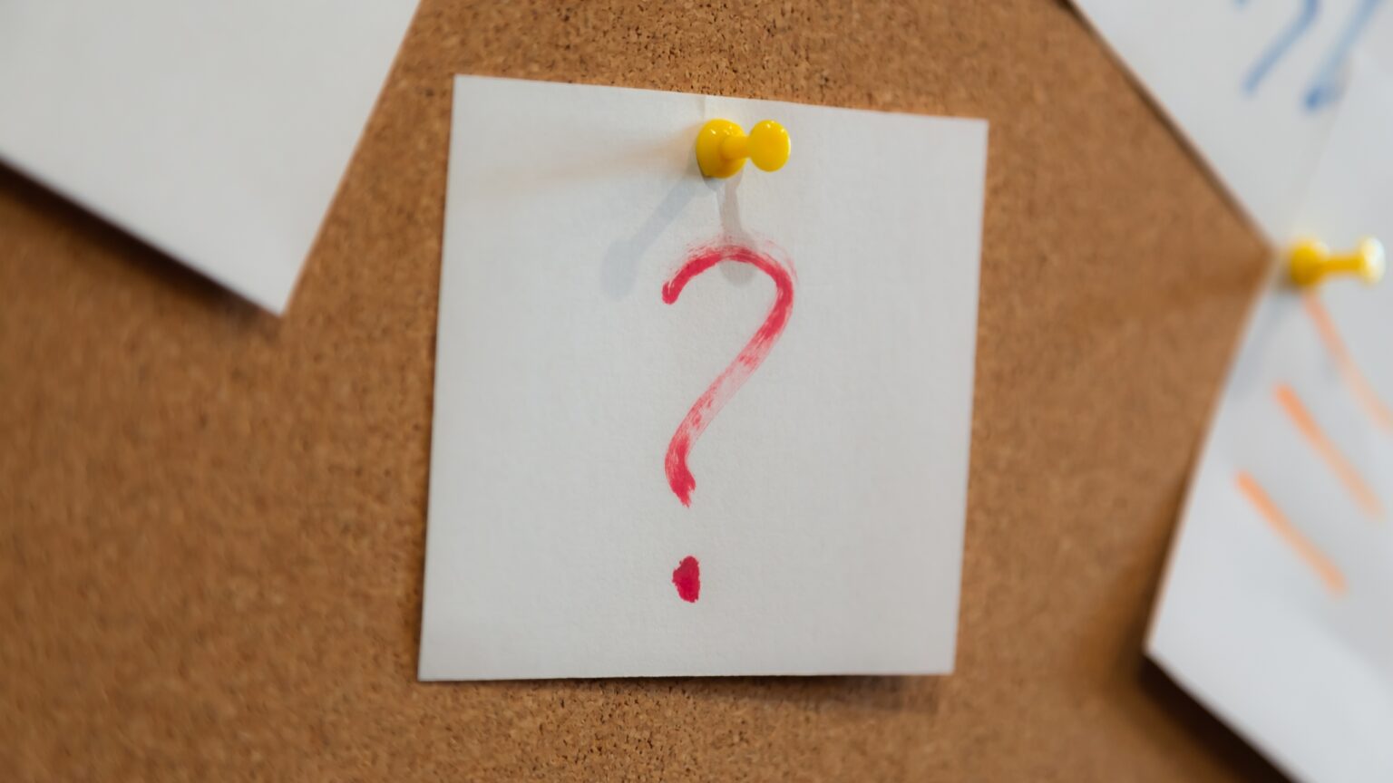 Red question mark on a piece of paper and many papers. Question concept.